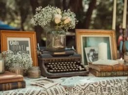 Vintage typewriter, books, candles, and flowers create a charming graduation party tablescape. 