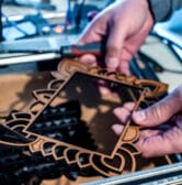 Close-up of hands holding a laser-cut wooden frame.